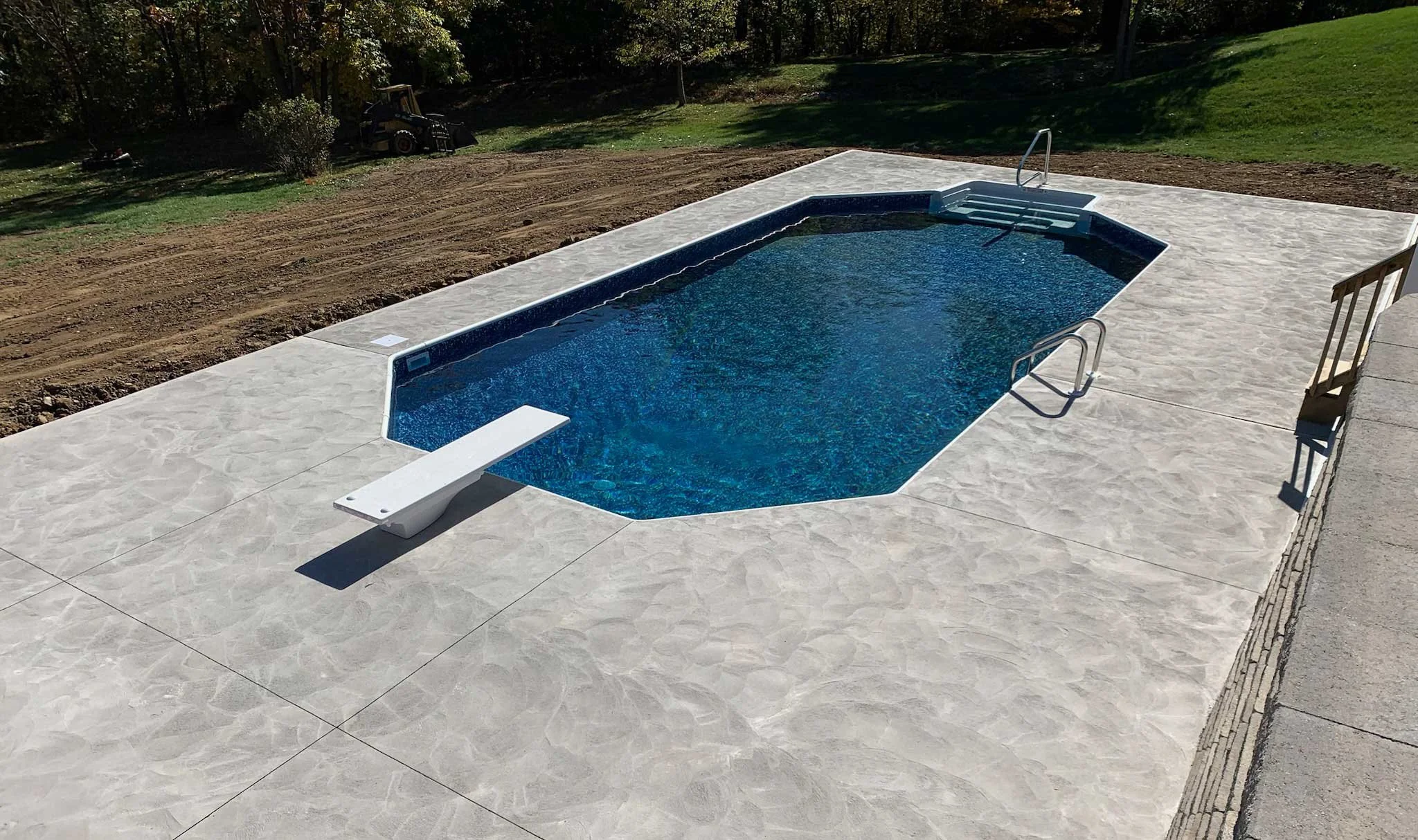 In-ground pool featuring a diving board, entry steps, and decorative concrete patio