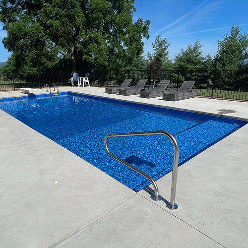 Custom backyard swimming pool with blue liner, concrete decking, and poolside seating area.