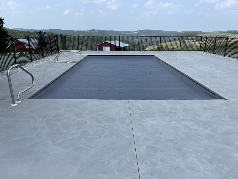 In-ground swimming pool prepared for winter with a safety cover installed for seasonal protection.