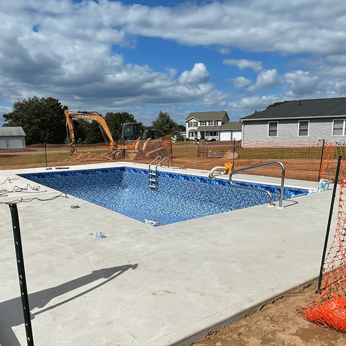 New in-ground swimming pool installation by Man Made Pools during final stages of construction.