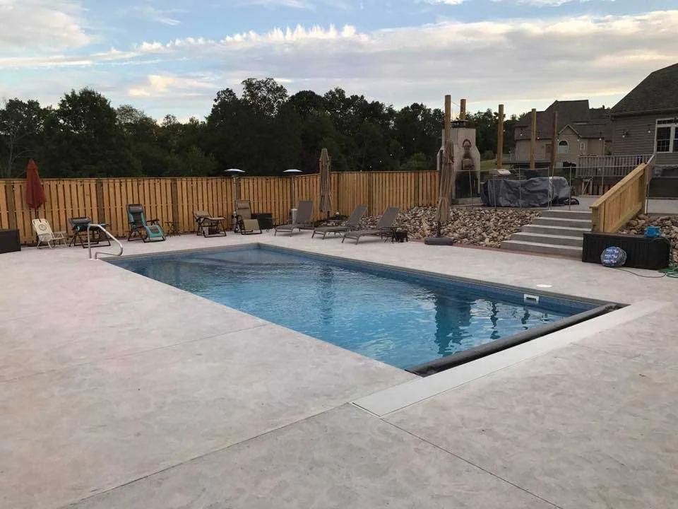 Rectangular in-ground swimming pool with spacious concrete deck and backyard entertaining area