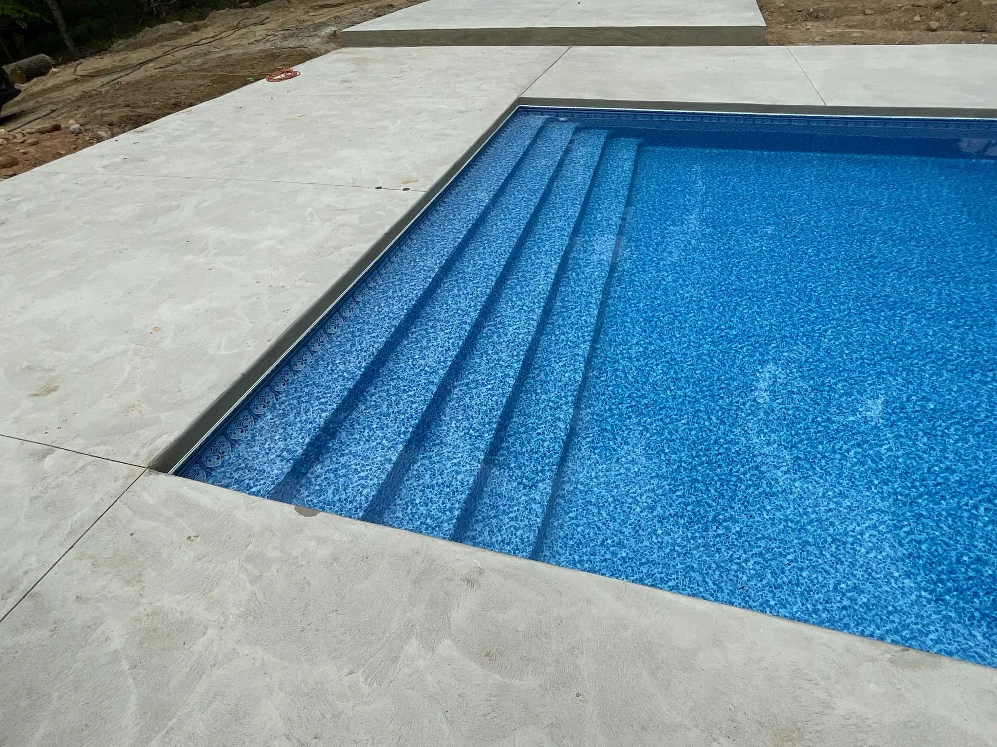Close-up of wide entry steps in a swimming pool with concrete pool deck