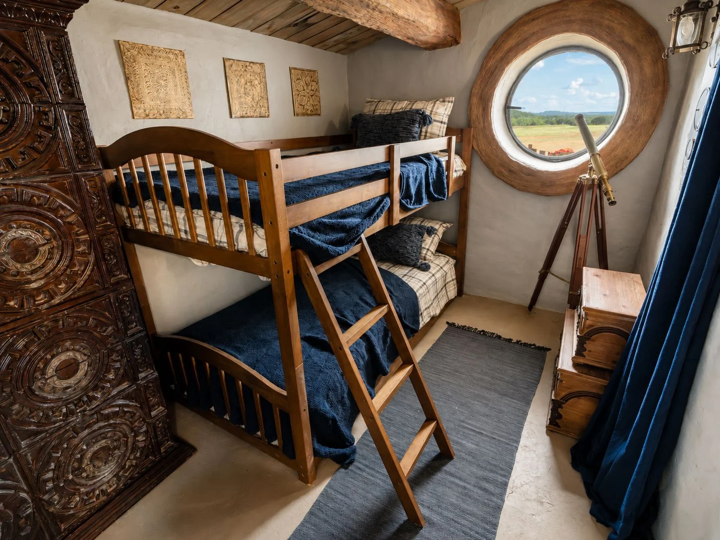 A cozy hobbit bedroom at Mirador Texas with a wooden bunk bed, an antique wooden cabinet, a telescope by a round window, and a scenic view of green fields outside.