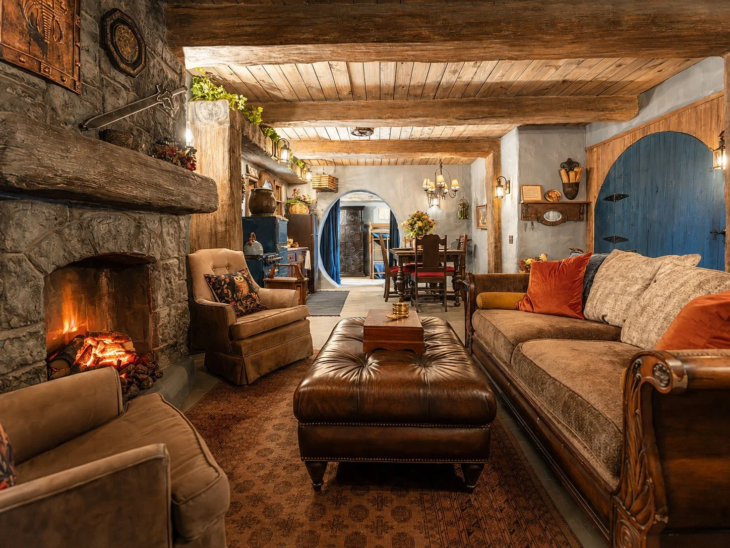 Cozy hobbit living room at Mirador Texas with stone fireplace, leather and fabric sofas, wooden furniture, and rustic decor.