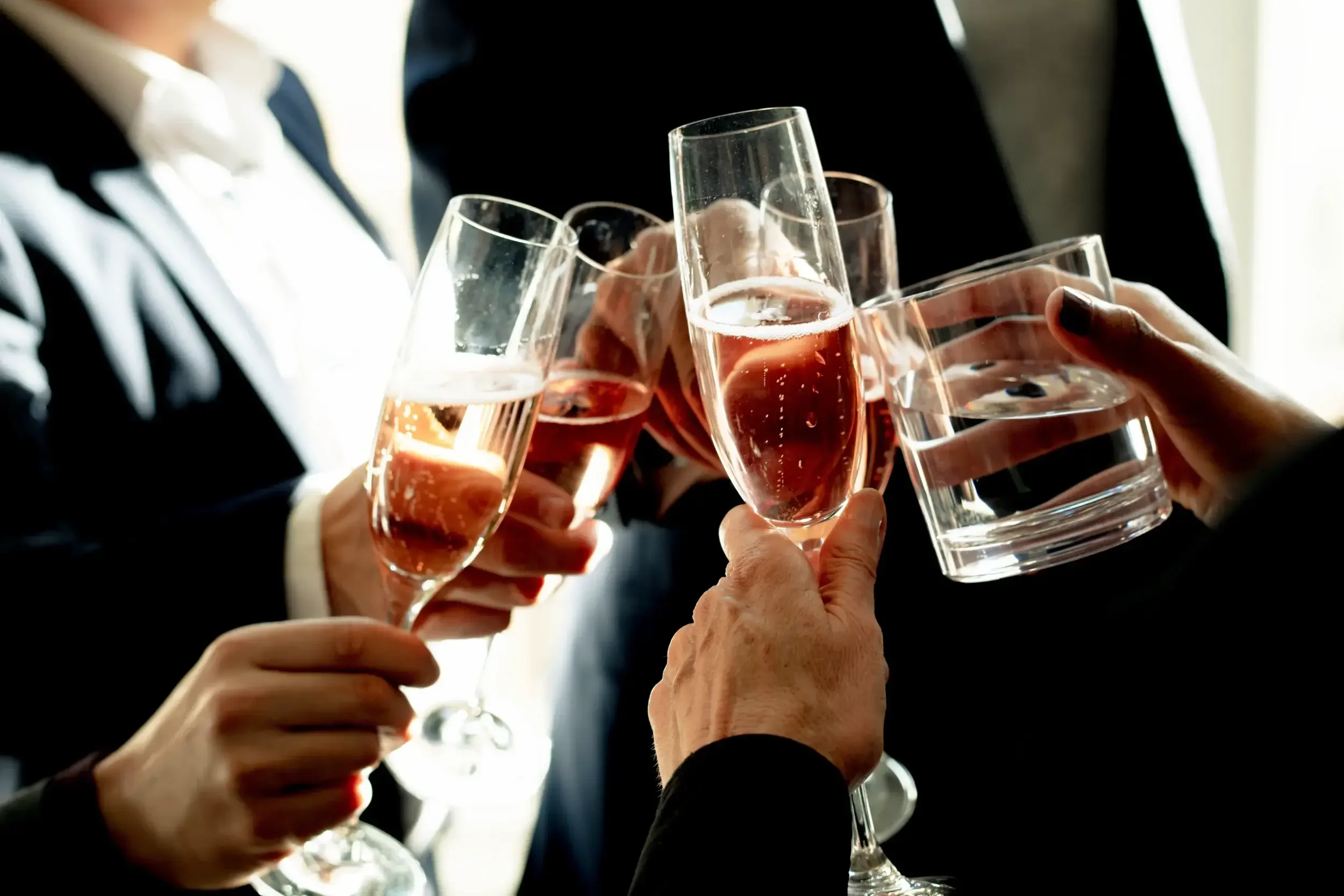 Several people in formal attire clinking glasses of champagne in a toast.