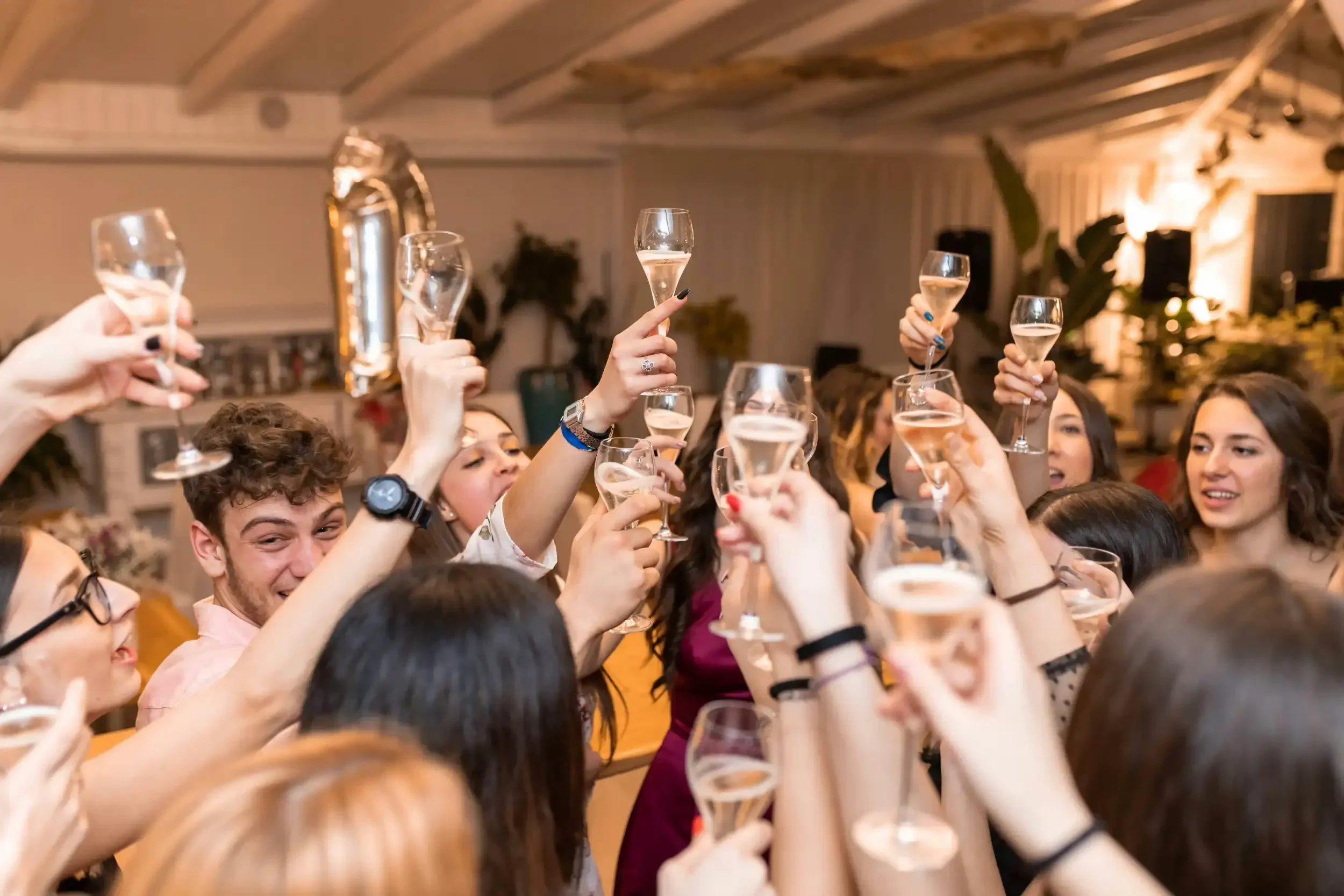 Group of people celebrating indoors, raising glasses of champagne in toast.