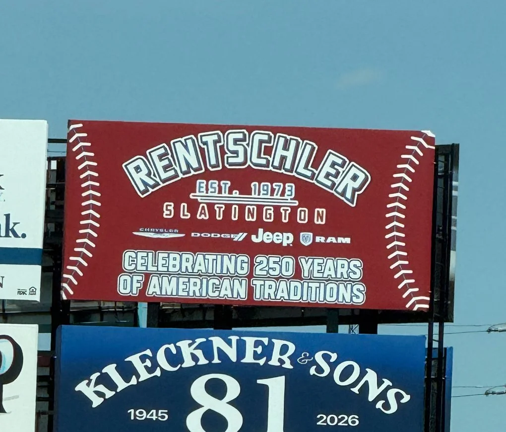 Billboard for Rentschler Slaton, established 1973, celebrating 250 years of American car traditions, featuring logos of Chrysler, Dodge, Jeep, and RAM. Another billboard below for Kleckner & Sons, 81 years from 1945 to 2026.