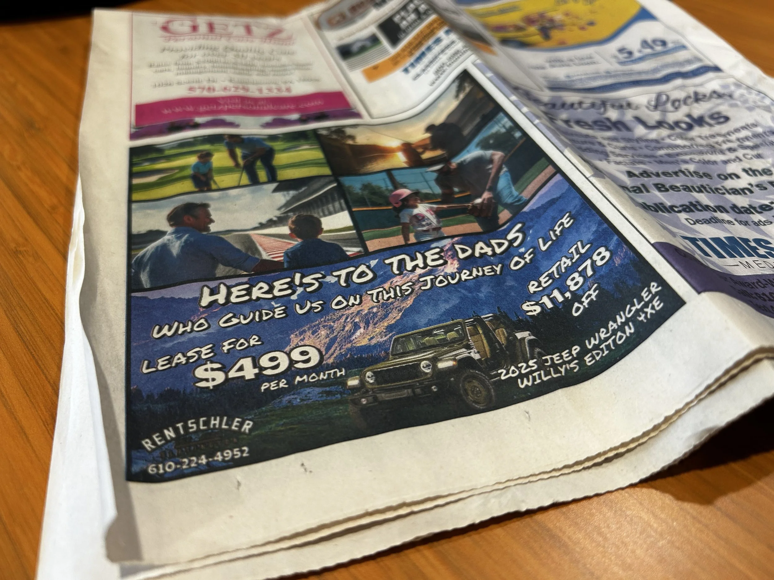 A crumpled newspaper page featuring an advertisement for leasing a 2025 Jeep Wrangler Willys Edition for $499 per month, with images of people and a Jeep vehicle on a street or parking lot.