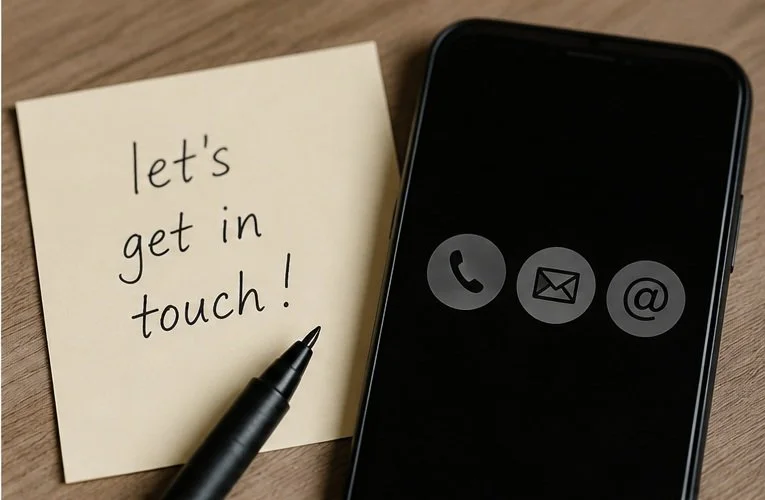 A sticky note with the handwritten message 'let's get in touch!' placed on a wooden surface next to a smartphone and a black pen.