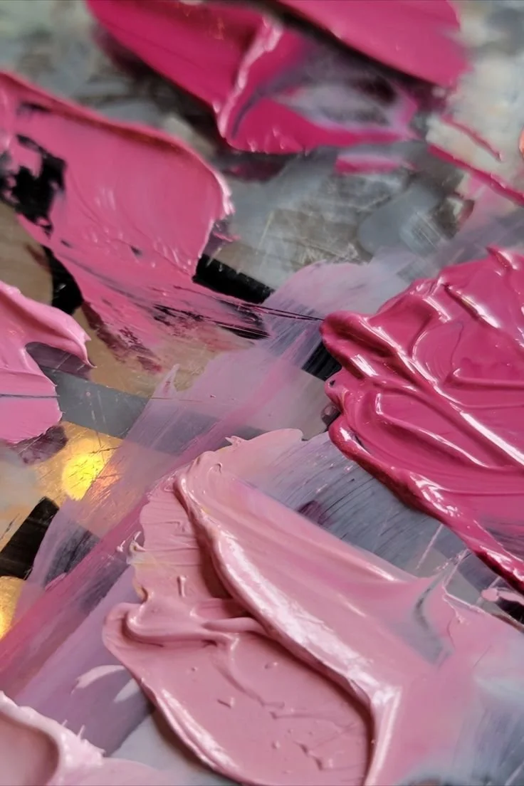 Close-up of pink and light pink paint smears and strokes on a surface.