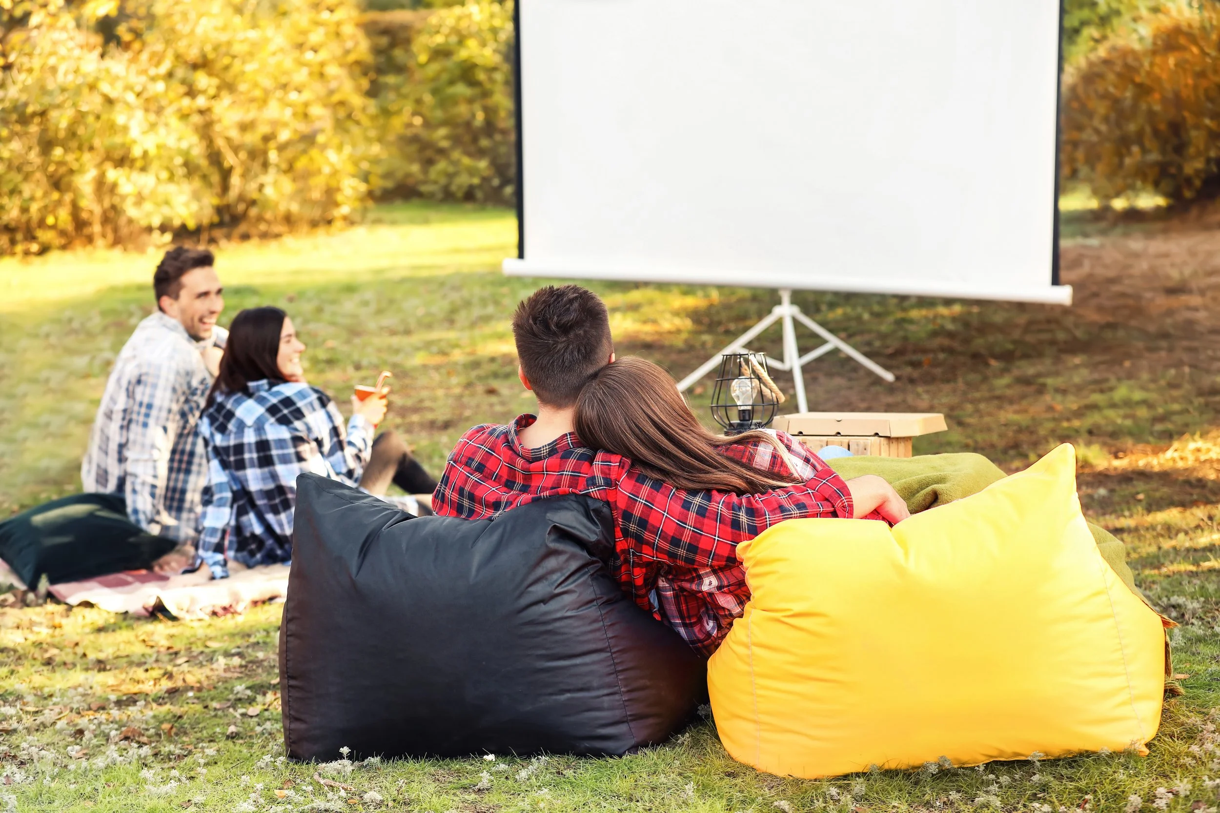 Couple watches movie on projector screen in backyard