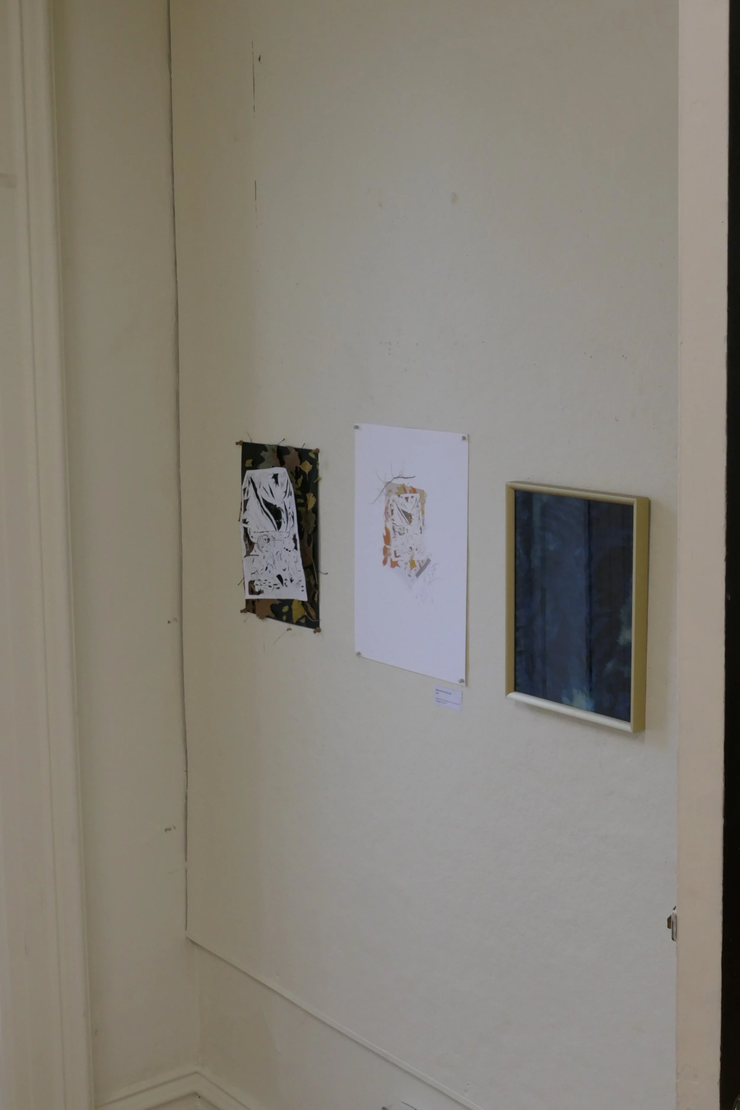 Gallery wall with two artworks and a framed fabric piece on a beige wall.