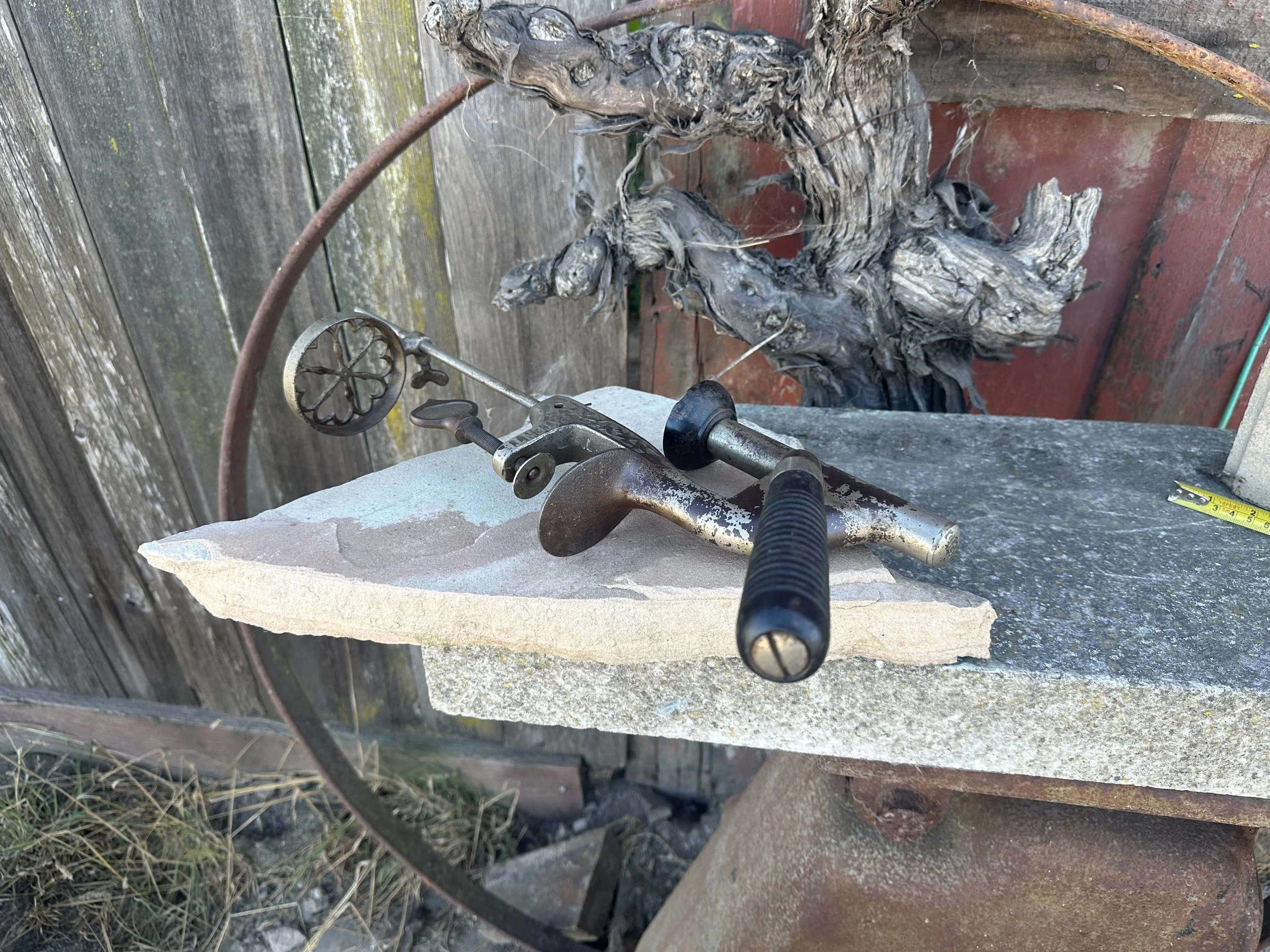 A metal bottle capper laying atop two pieces of stone.