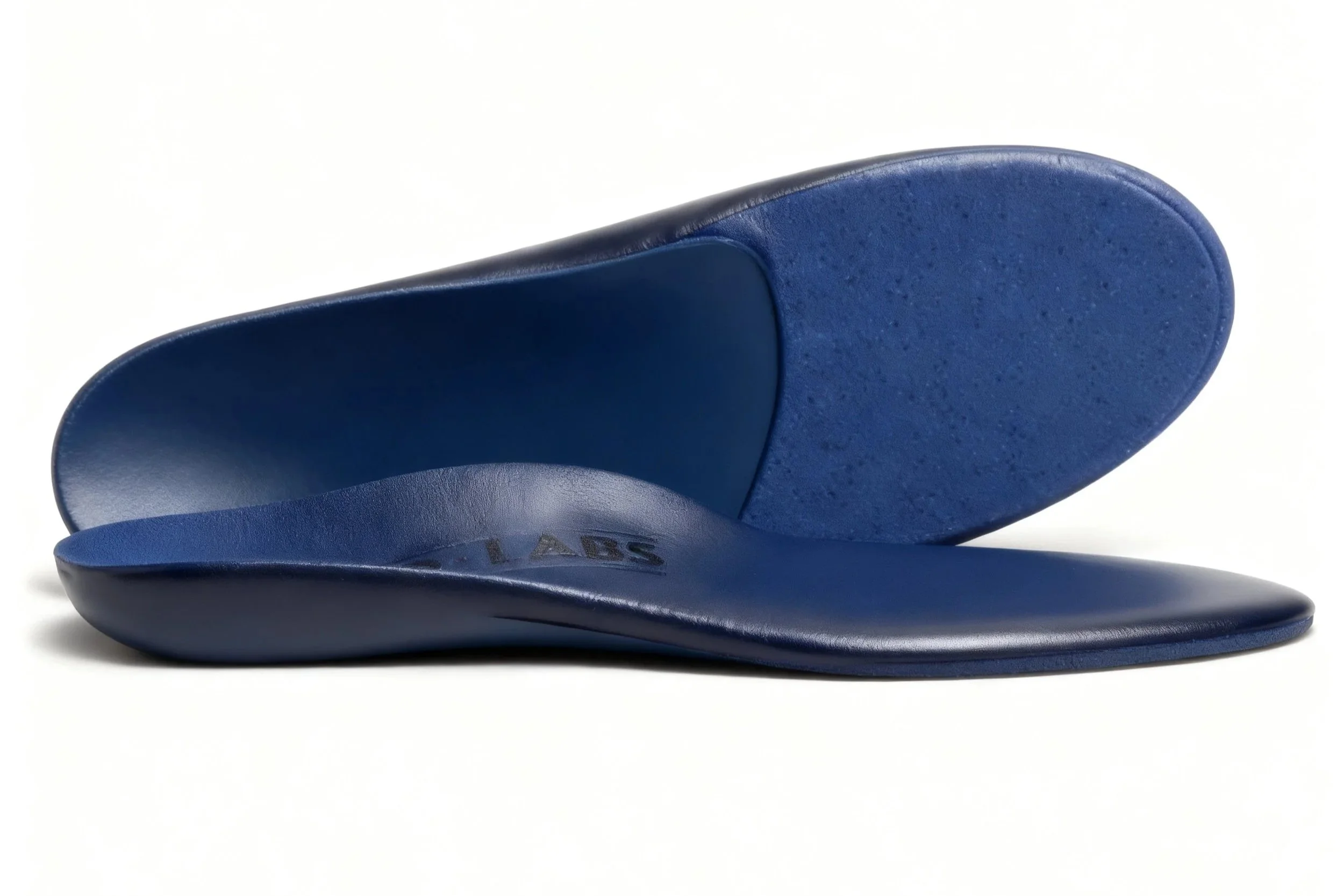 Close-up of a blue orthotic shoe insert or insole made of foam and plastic, with a textured surface, placed on a white background.