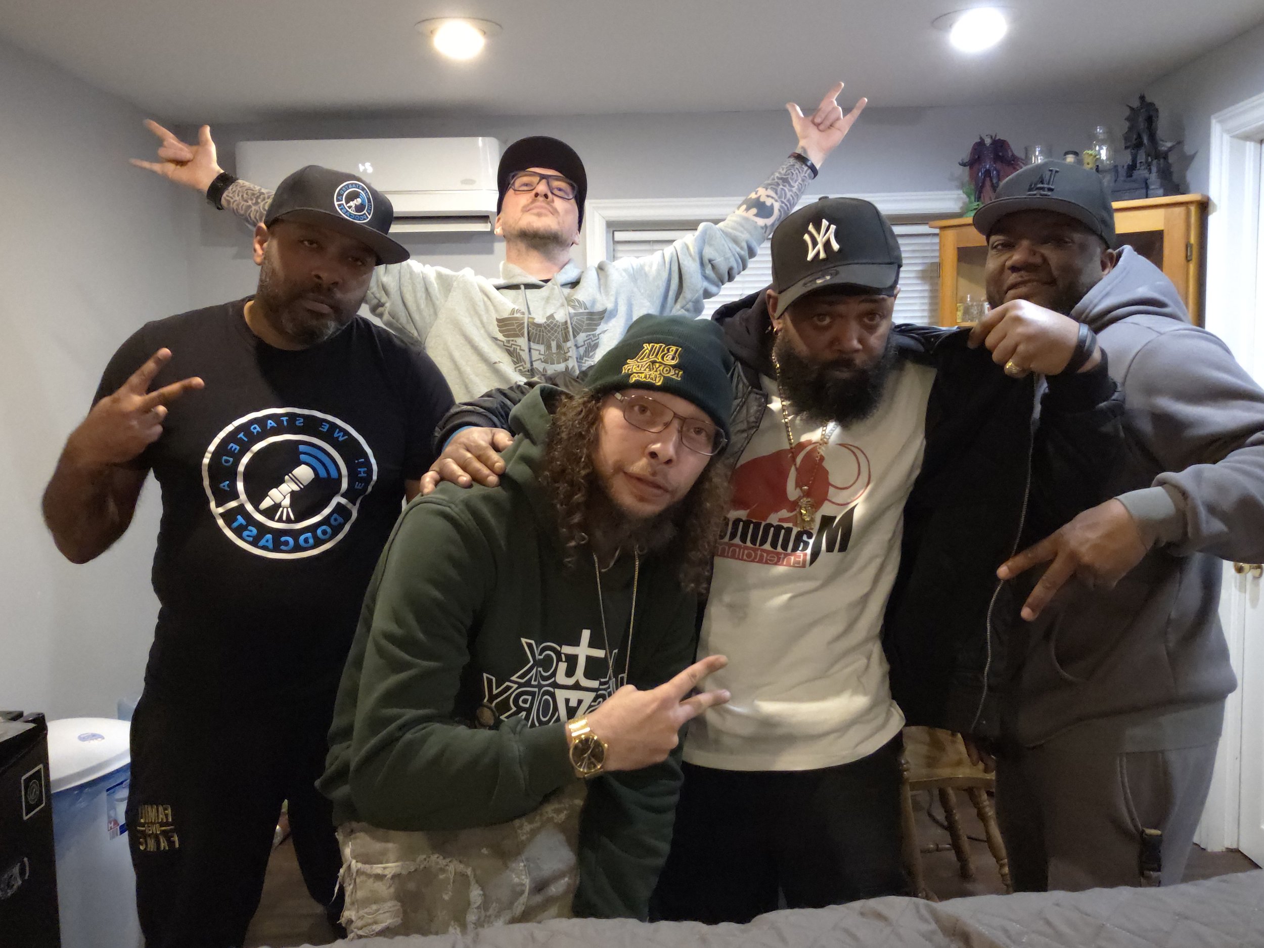 Jon Kizzy. Ray Rey, Knucklehead and King Tygga posing together indoors, some making hand gestures, in casual clothing and hats.
