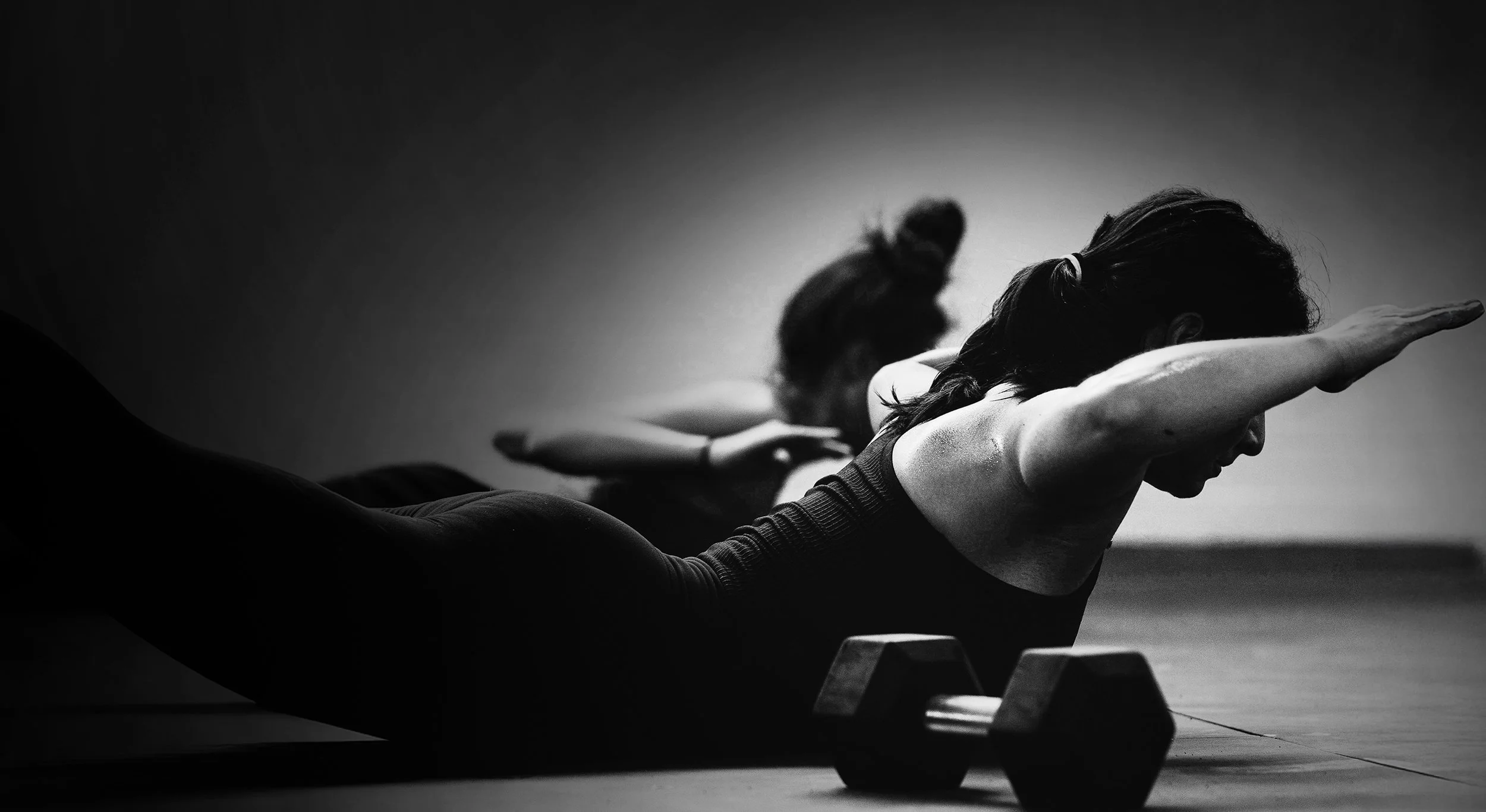 Zwei Frauen machen Fitnessübungen auf dem Boden, eine Hantel liegt im Vordergrund. Das Kampagnenmotiv „Gesund bleiben braucht Nähe“ steht für die Unterstützung der Betriebskrankenkassen im Bereich Prävention und Gesundheitsförderung.