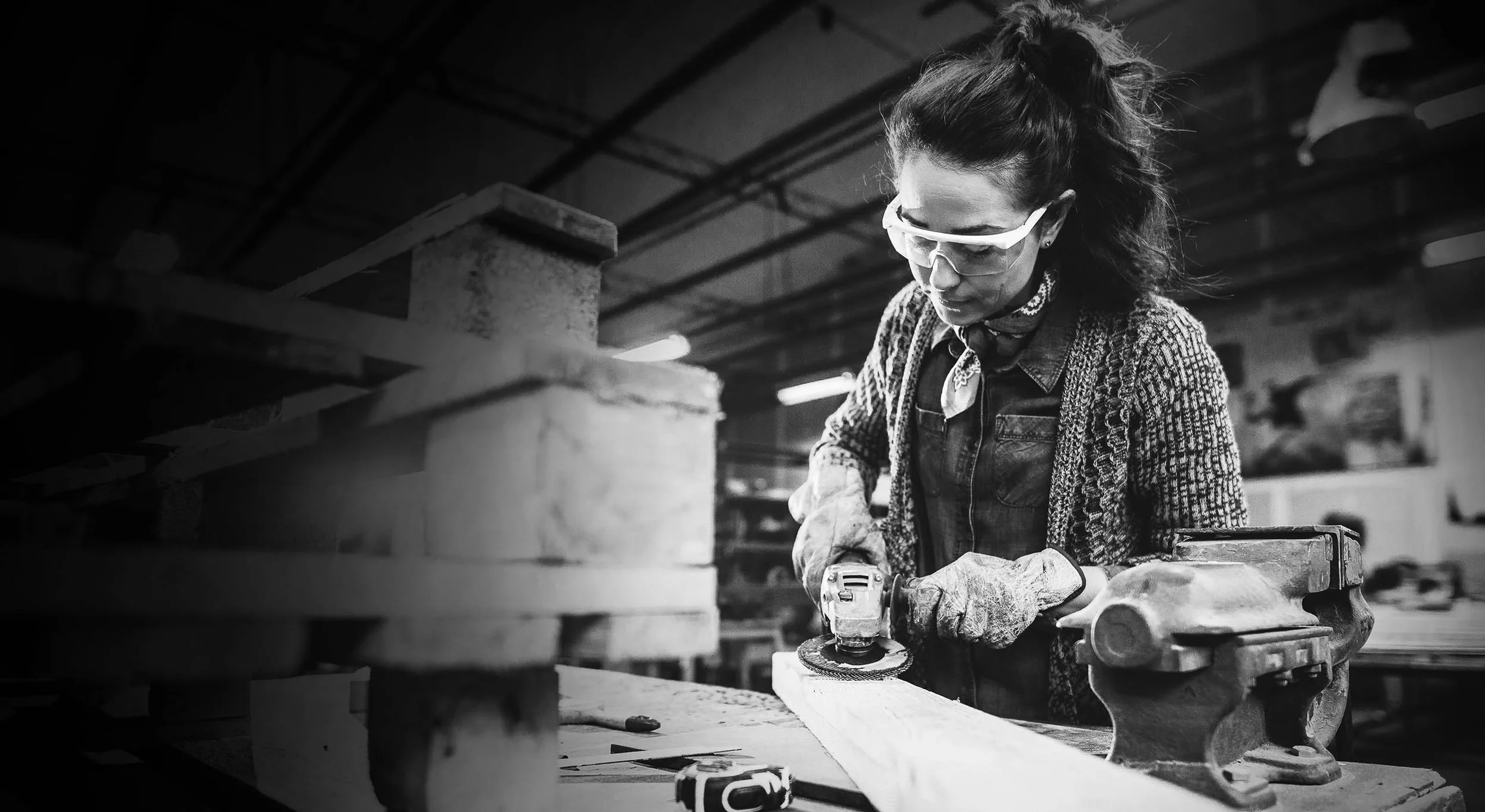 Frau mit Schutzbrille arbeitet an einem Werkstück in einer Werkstatt. Das Dachmotiv der BKK-Kampagne „Gesunde Nähe. Jeden Tag.“ symbolisiert die enge Verbindung der Betriebskrankenkassen zu regionalen Unternehmen und ihren Beschäftigten.