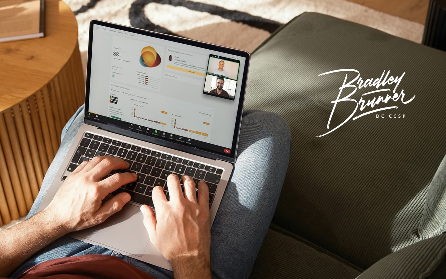 Person working on a laptop on their lap, with a video call window open and the name 'Bradley Brunner' written on a nearby green cushion.