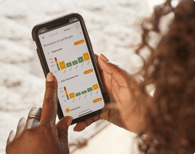 Person holding a smartphone displaying biomarker and lab results charts.