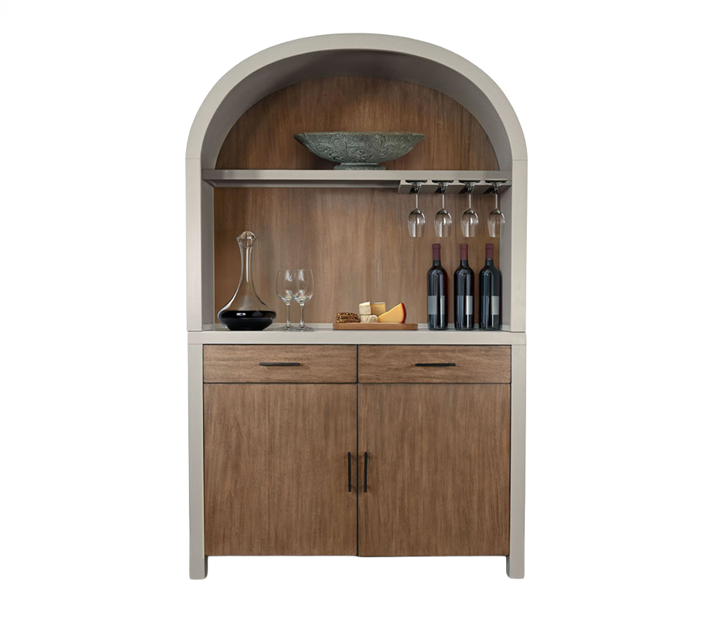 A wooden bar cabinet with a curved top, displaying wine bottles, glasses, a decanter, cheese, and a decorative bowl inside.