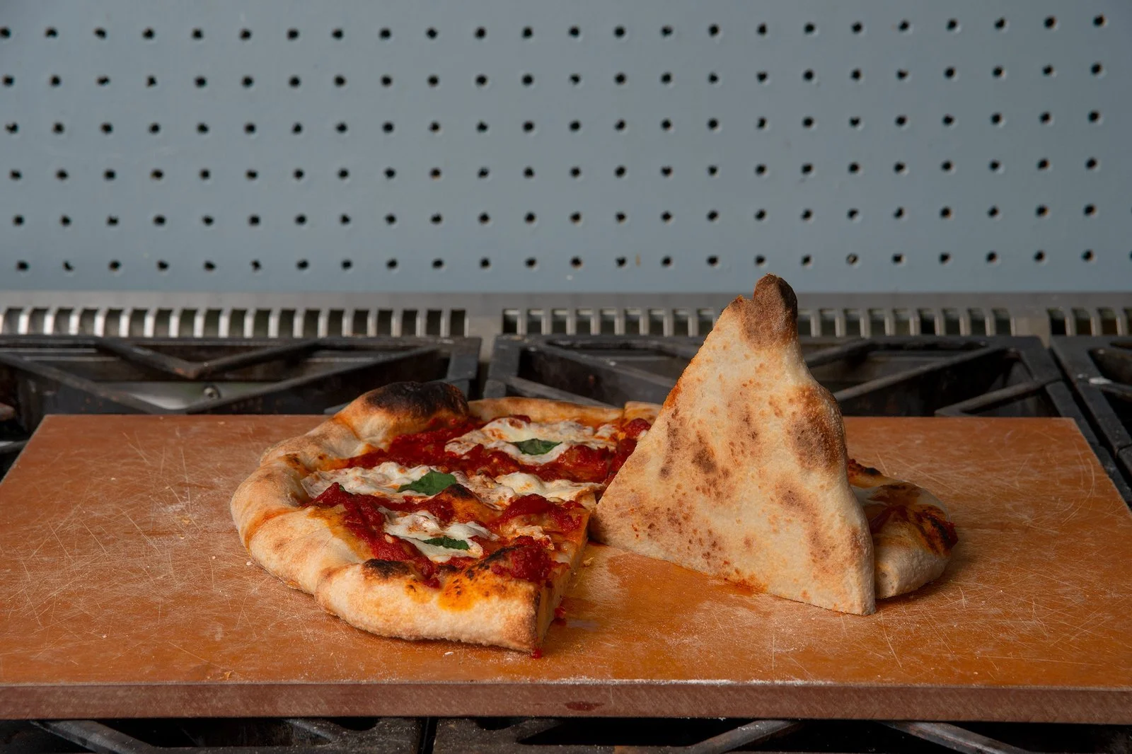 Pizza slices on Borough Furnace cast iron pizza griddle on stovetop