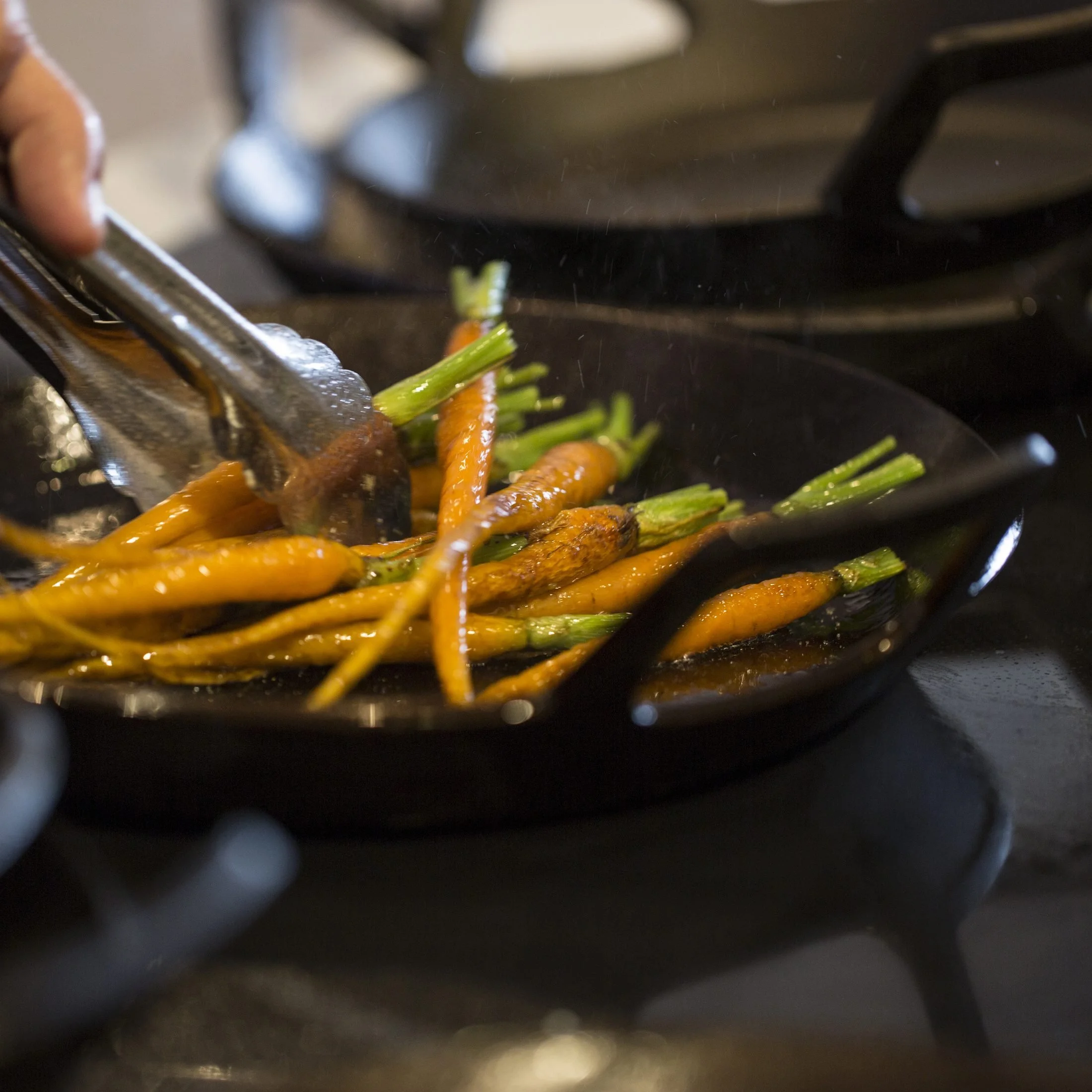 Carrots simmering in a cast iron skillet on an induction cooktop