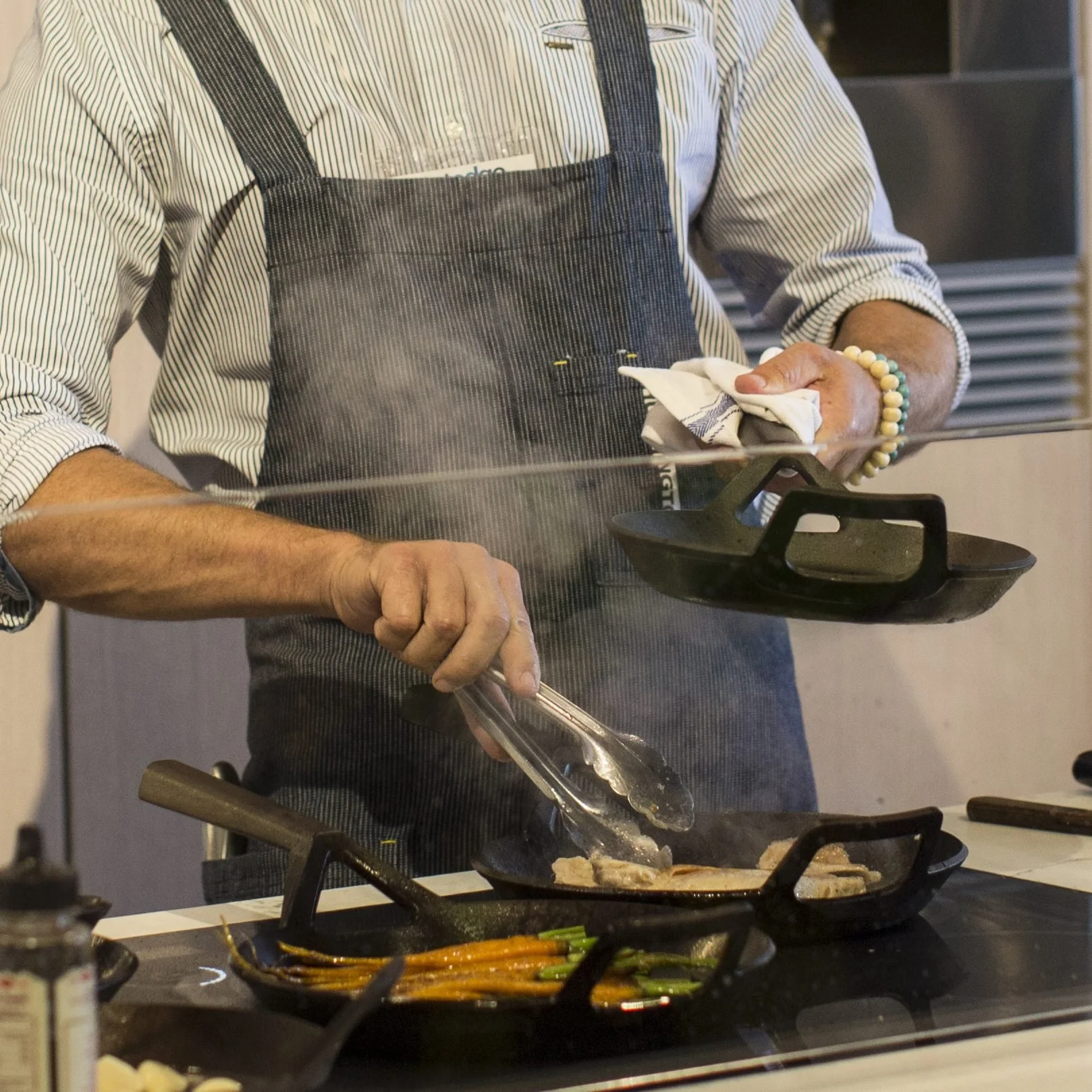 A chef with four Borough Furnace cast iron skillets on an induction cooktop