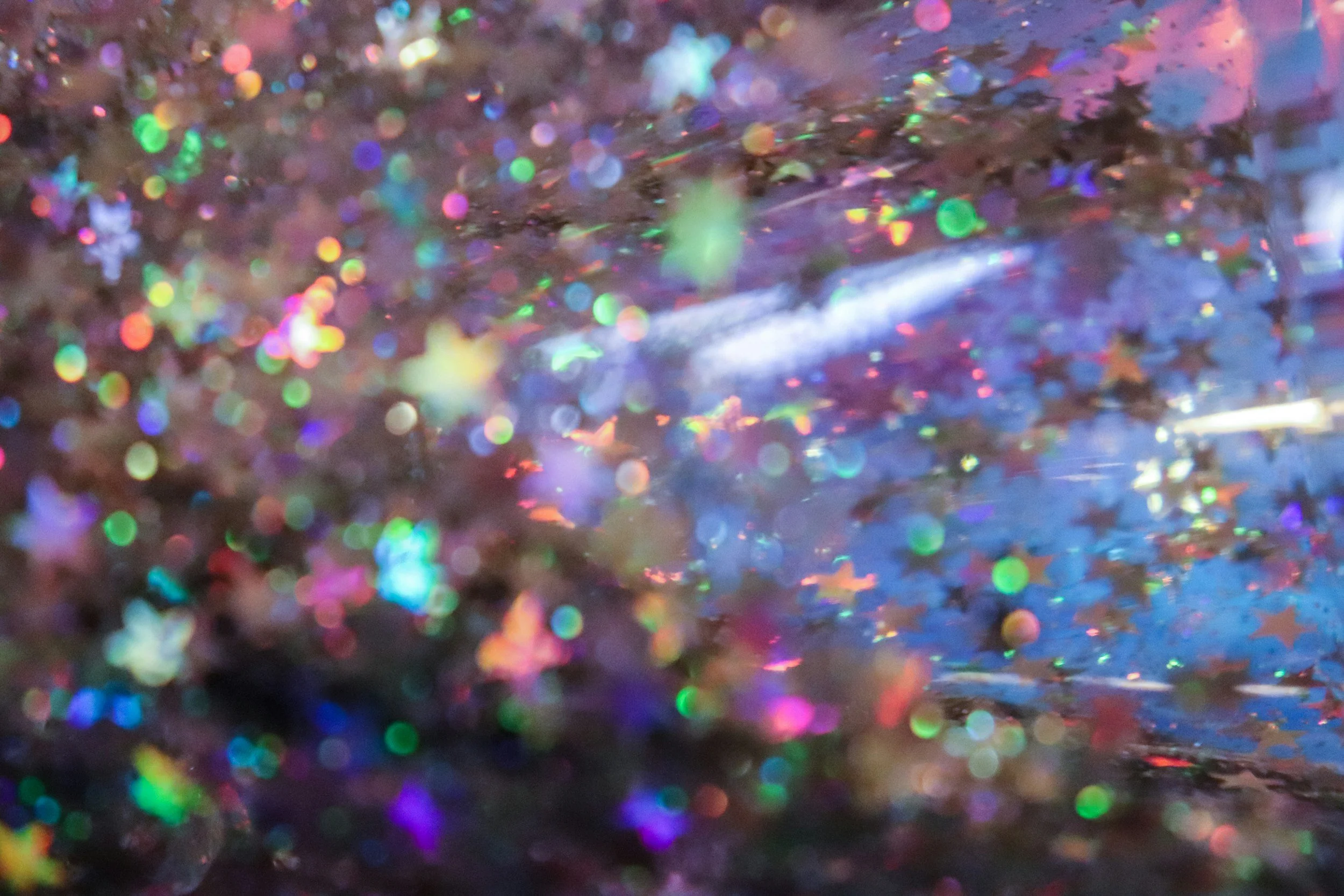 Close-up view of colorful holographic glitter with shiny, iridescent particles reflecting light.