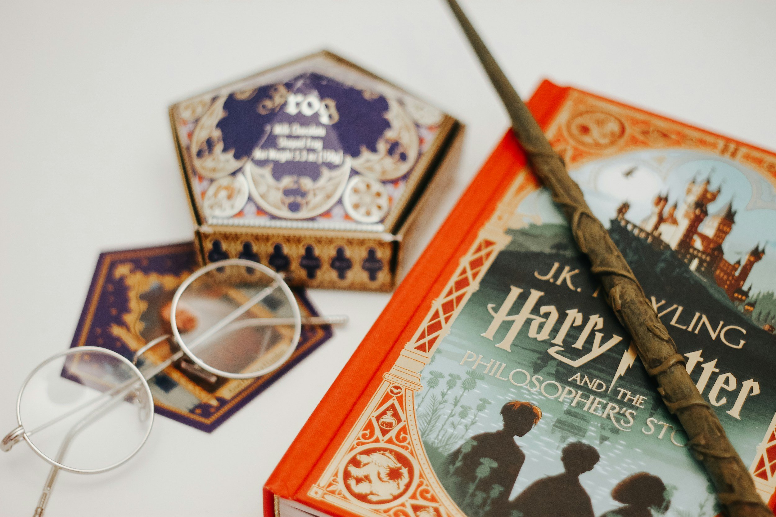 Close-up of a book titled 'Harvey' among other books and items on a white surface, with a stick-like object resting on it.