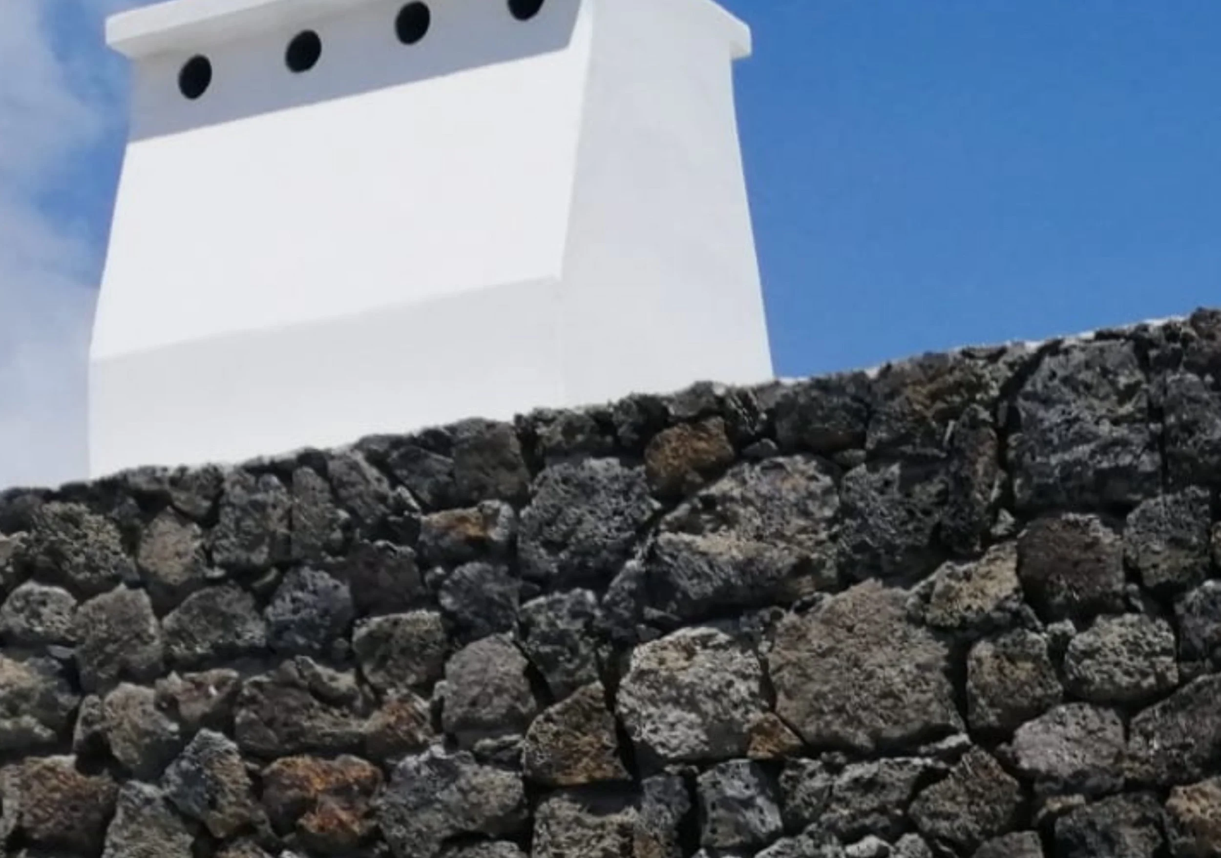 A large white structure, possibly a church or monument, on a hill, seen against a cloudy sky.