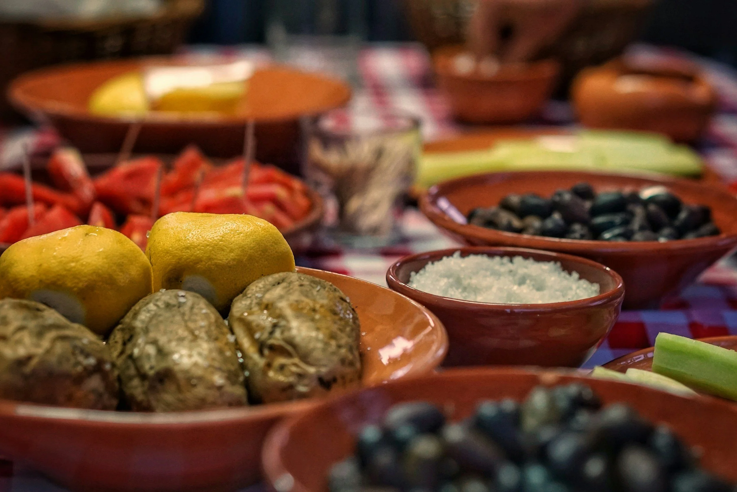 A variety of colorful bowls with lemons, berries, nuts, and other food items on a table.