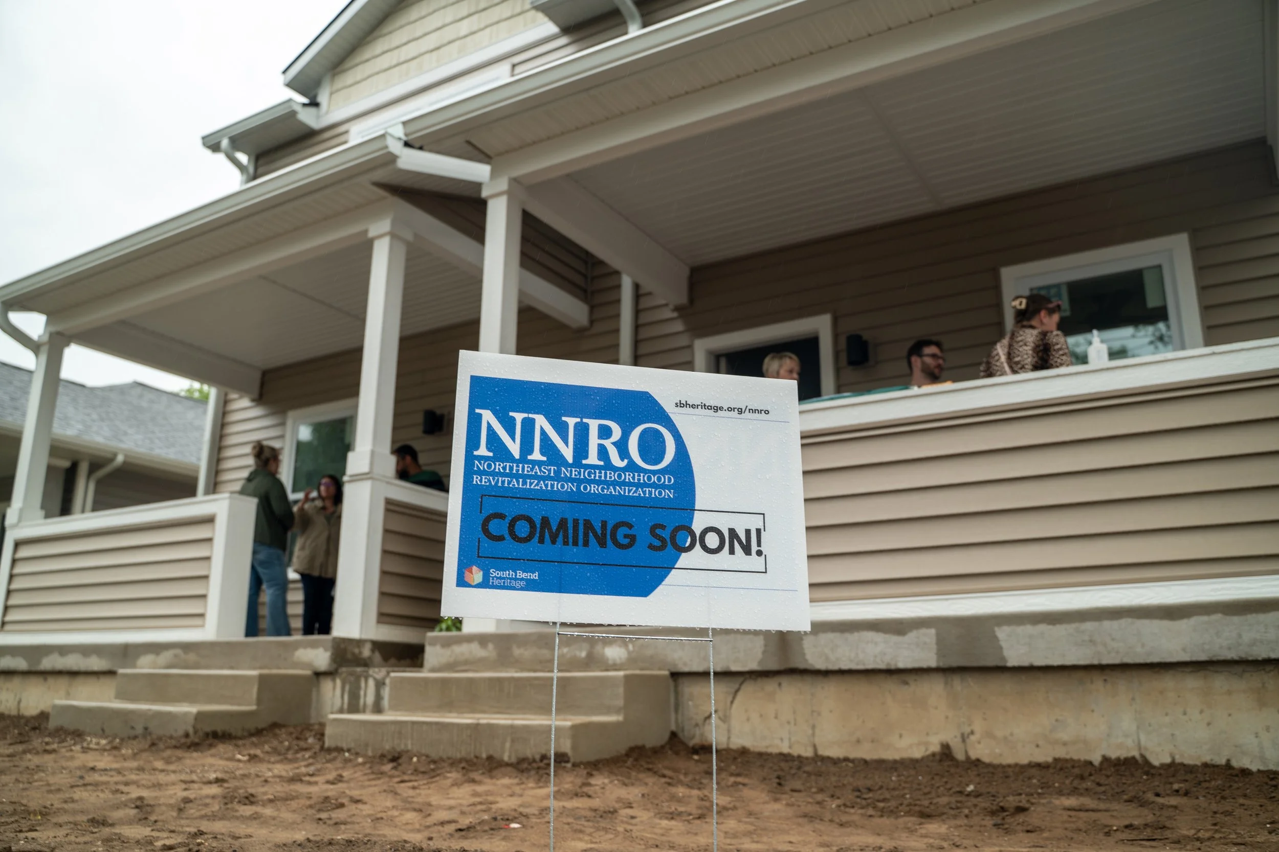 A house with a porch and a sign in the yard that reads 'NNRO Northeast Neighborhood Revitalization Organization Coming Soon'.