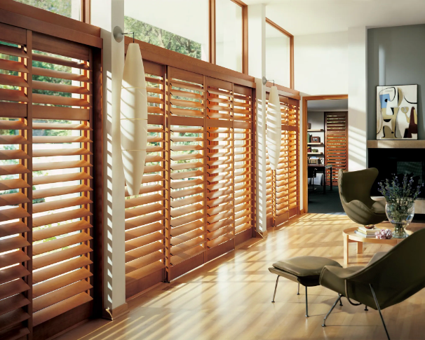 Natural wood plantation shutters on a wall of large windows in a bright contemporary room with hardwood floors