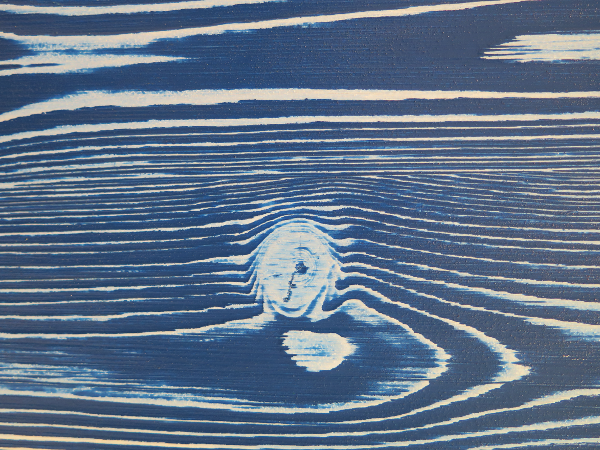 Close-up of a wood surface with a blue stain applied.