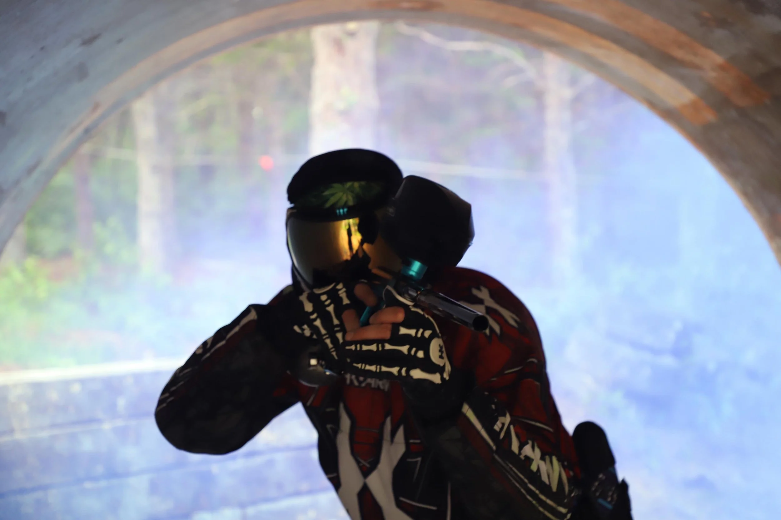 A person is holding a remote control while sitting in a cave or tunnel, with a view of a foggy, wooded landscape with a bridge visible through the opening.