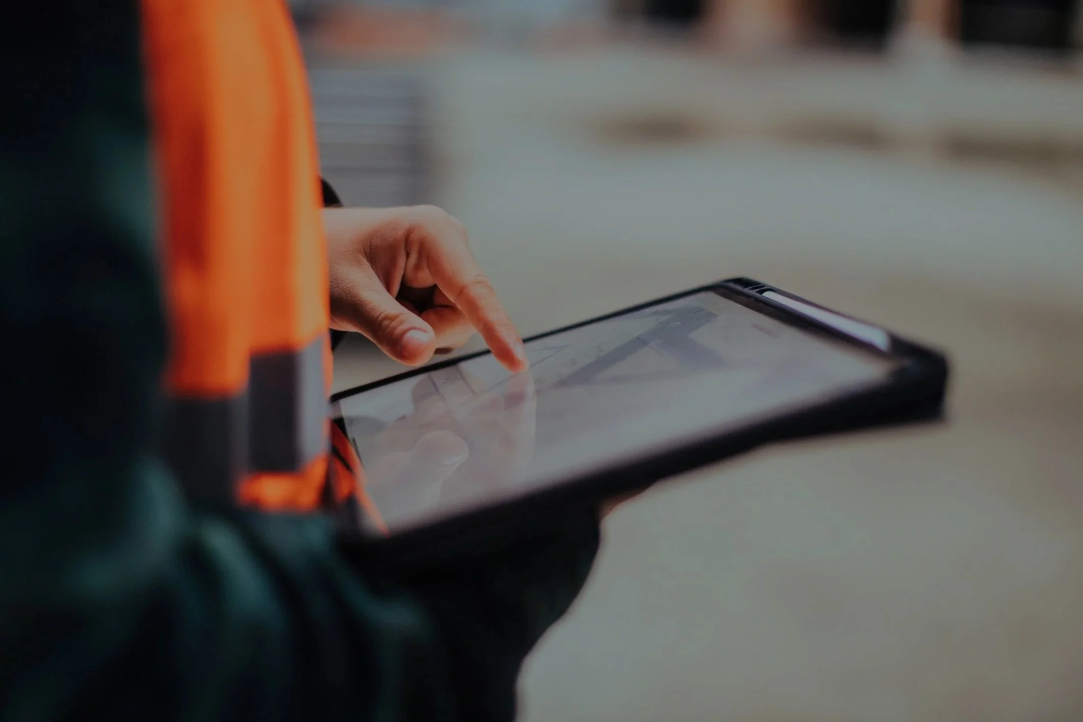 A person's hand using a touchscreen device, with a water bottle and some objects partially visible in the background.
