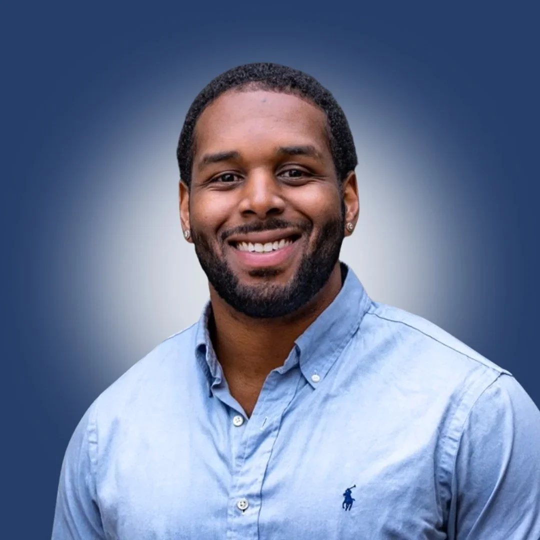 Dr. Alex Long wearing a light blue button-up shirt against a blue to white gradient background.