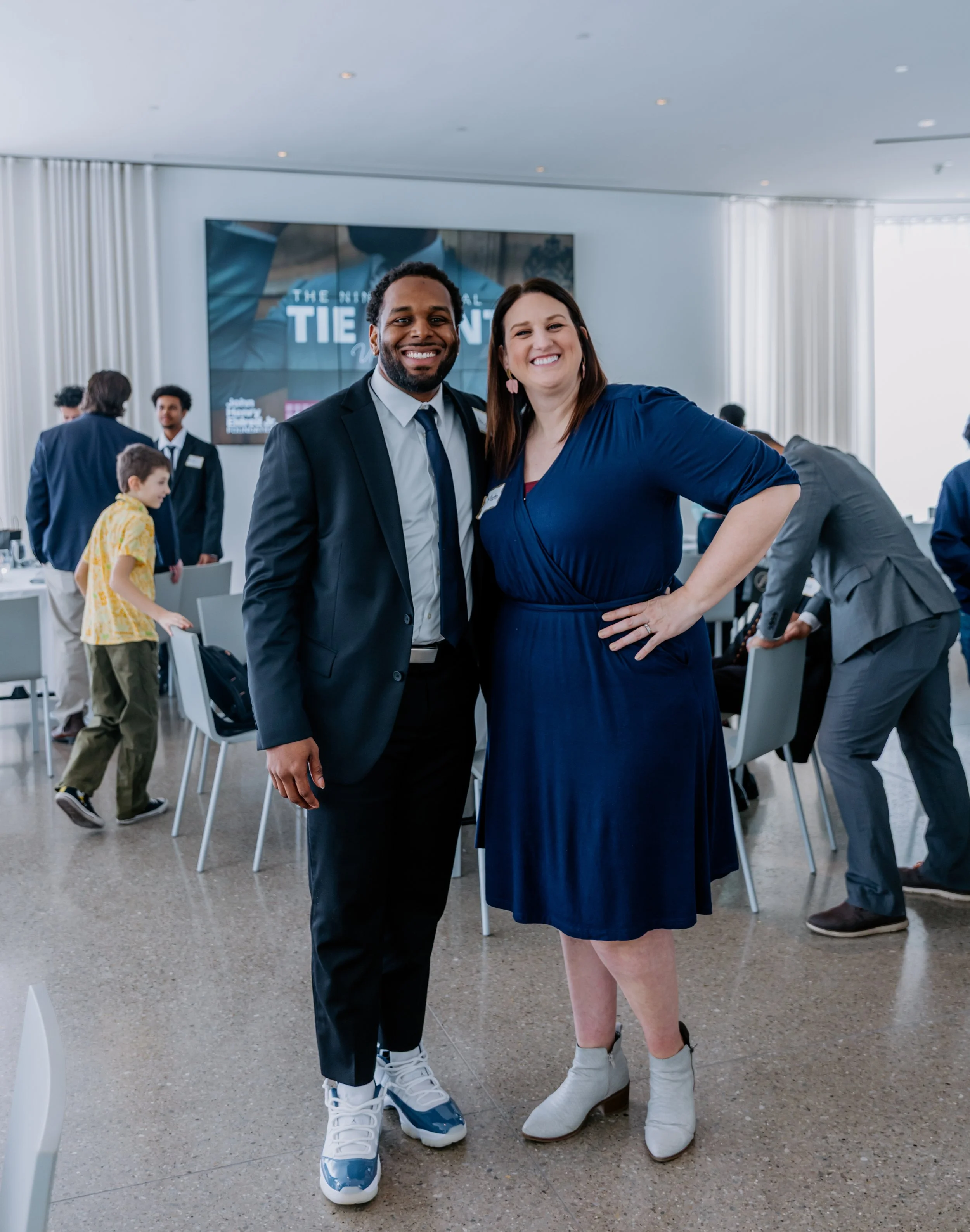 Dr. Alex Long and Dr. Andrea Mata taking a selfie at a formal event. The man is wearing a dark suit with a white shirt and a tie.