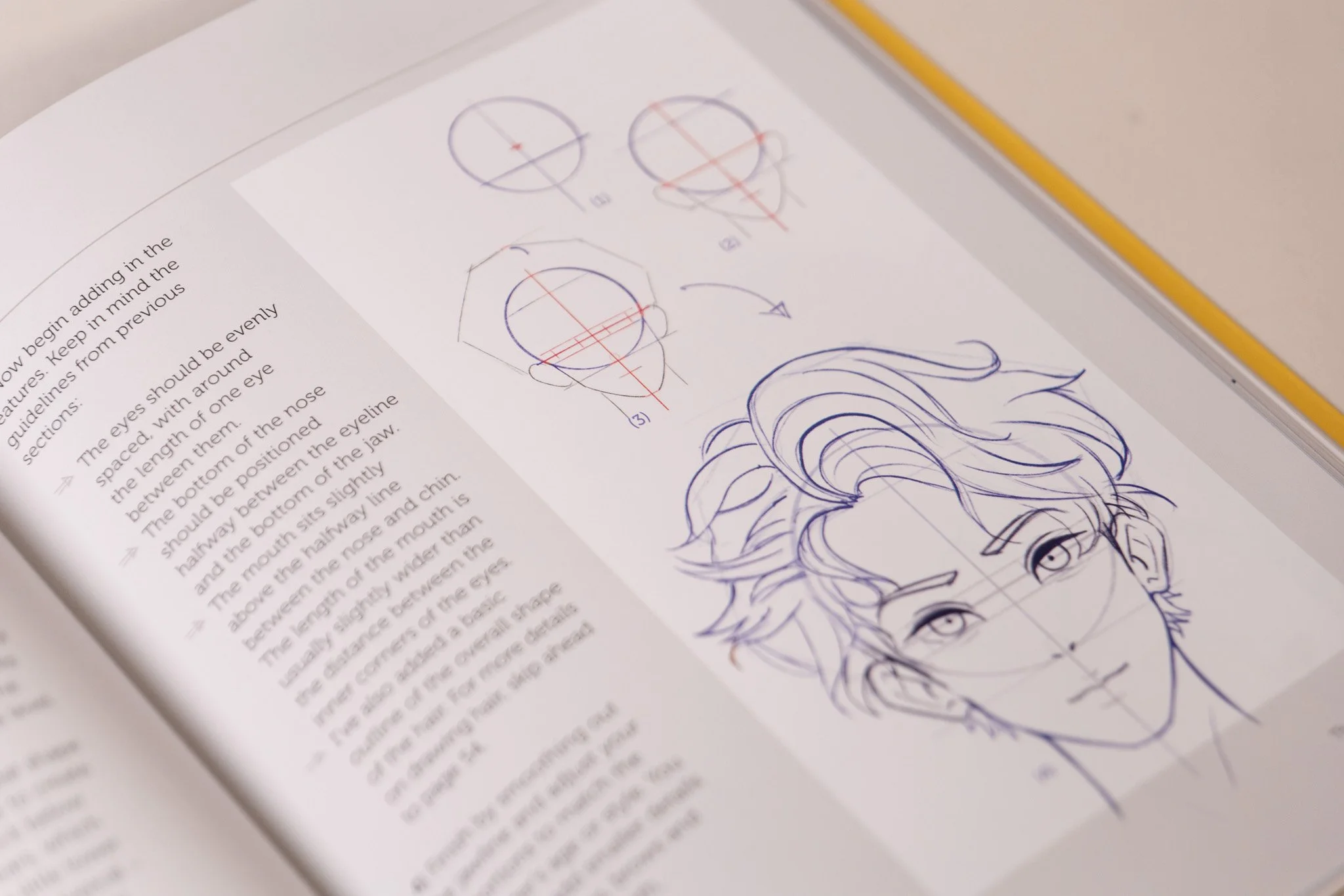 Open art instruction book displaying sketches of a person's head, face, and hair, along with diagrams and notes related to drawing features.
