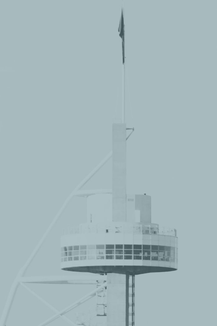 Close-up of a tall communications or observation tower with a circular observation deck near the top and structural elements extending upward.