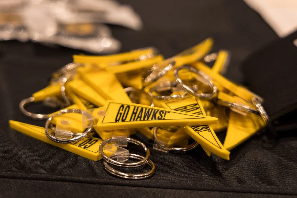 Yellow keychains with the text "GO HAWKS!" on a black surface.