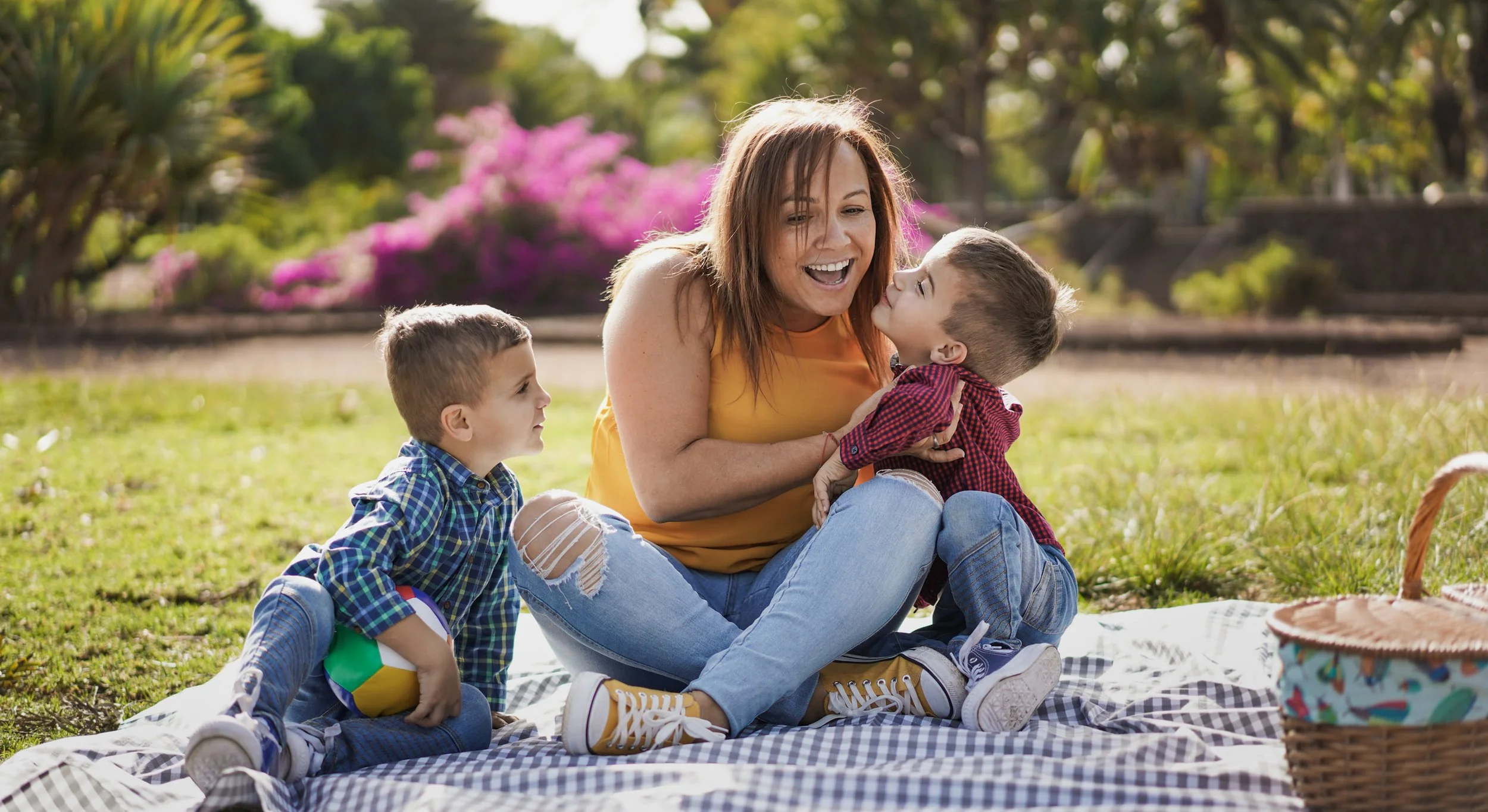 A mom having a picnic outside with 2 young boys