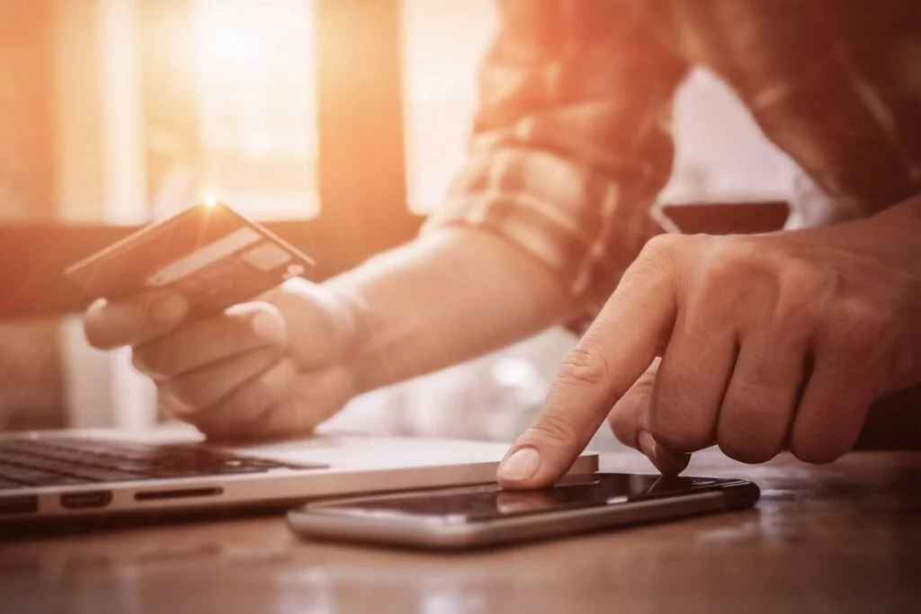 A man using his phone with debit card in the other hand