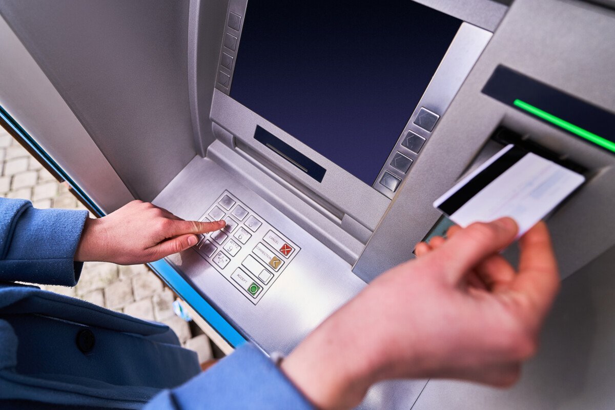 Someone typing their PIN number into an ATM machine