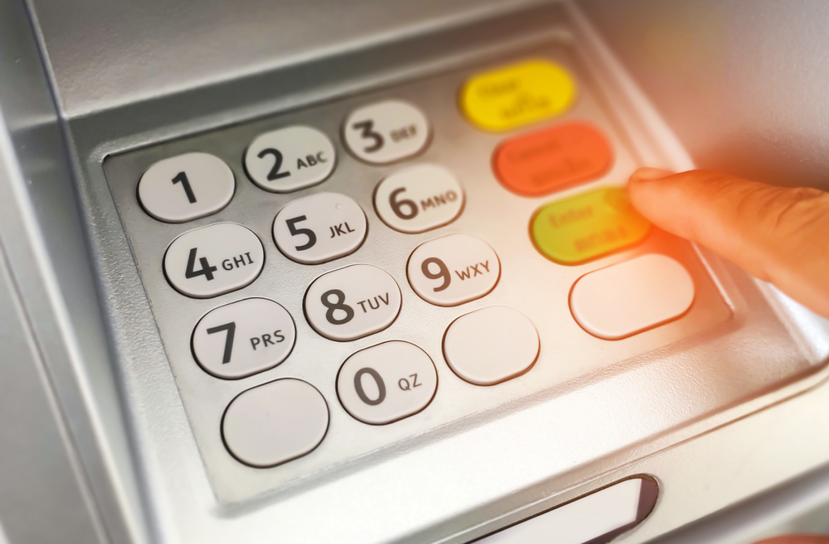 Person typing their PIN number into an ATM machine