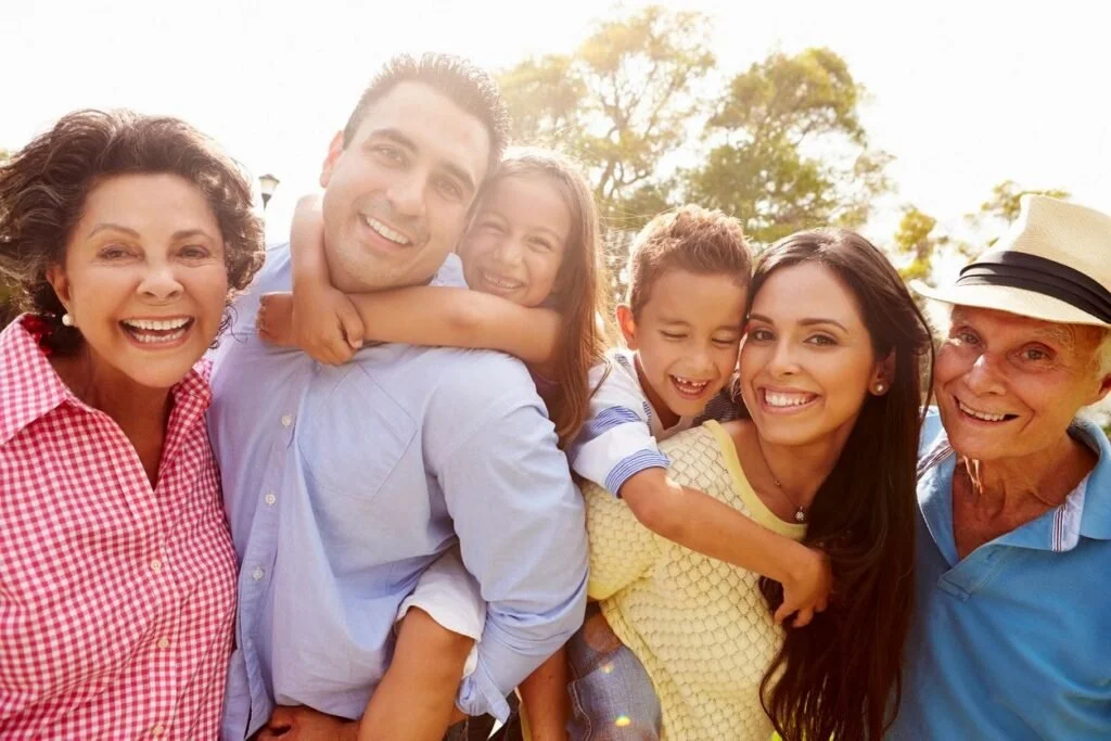 A family smiling at the camera with the sun in the background