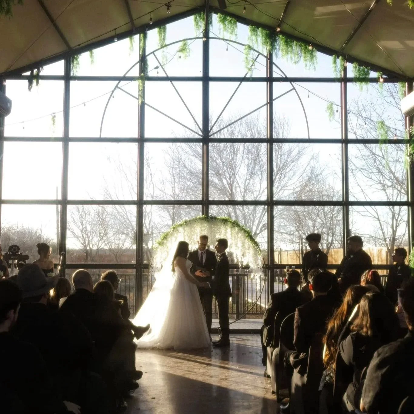 Wedding Guest observes ceremony with large glass windows framing the ceremony.