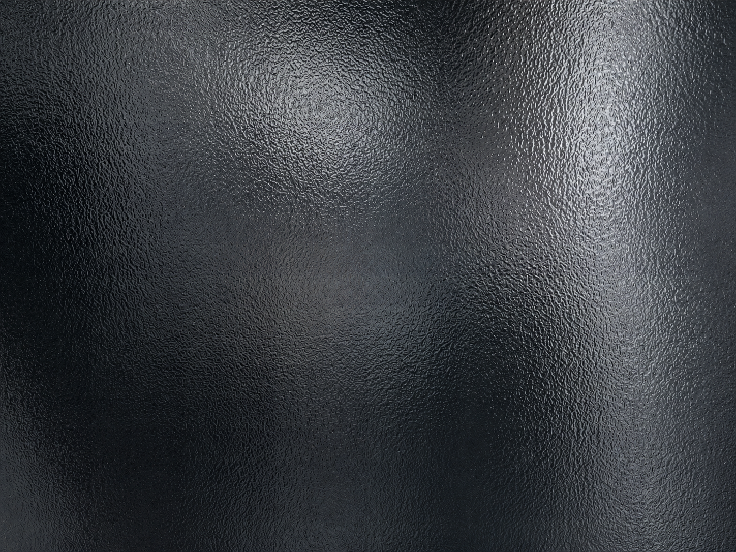 Close-up of a textured black surface, possibly leather or plastic, with a slightly reflective quality.
