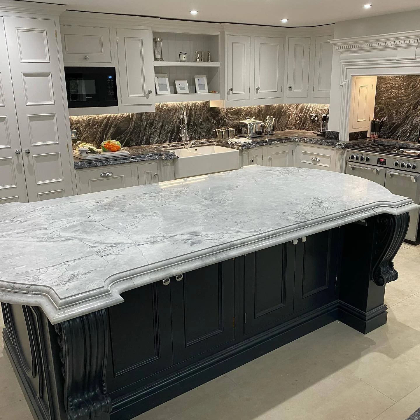 Modern kitchen with white cabinets, black and white marble countertops, and a large marble island with detailed black base.