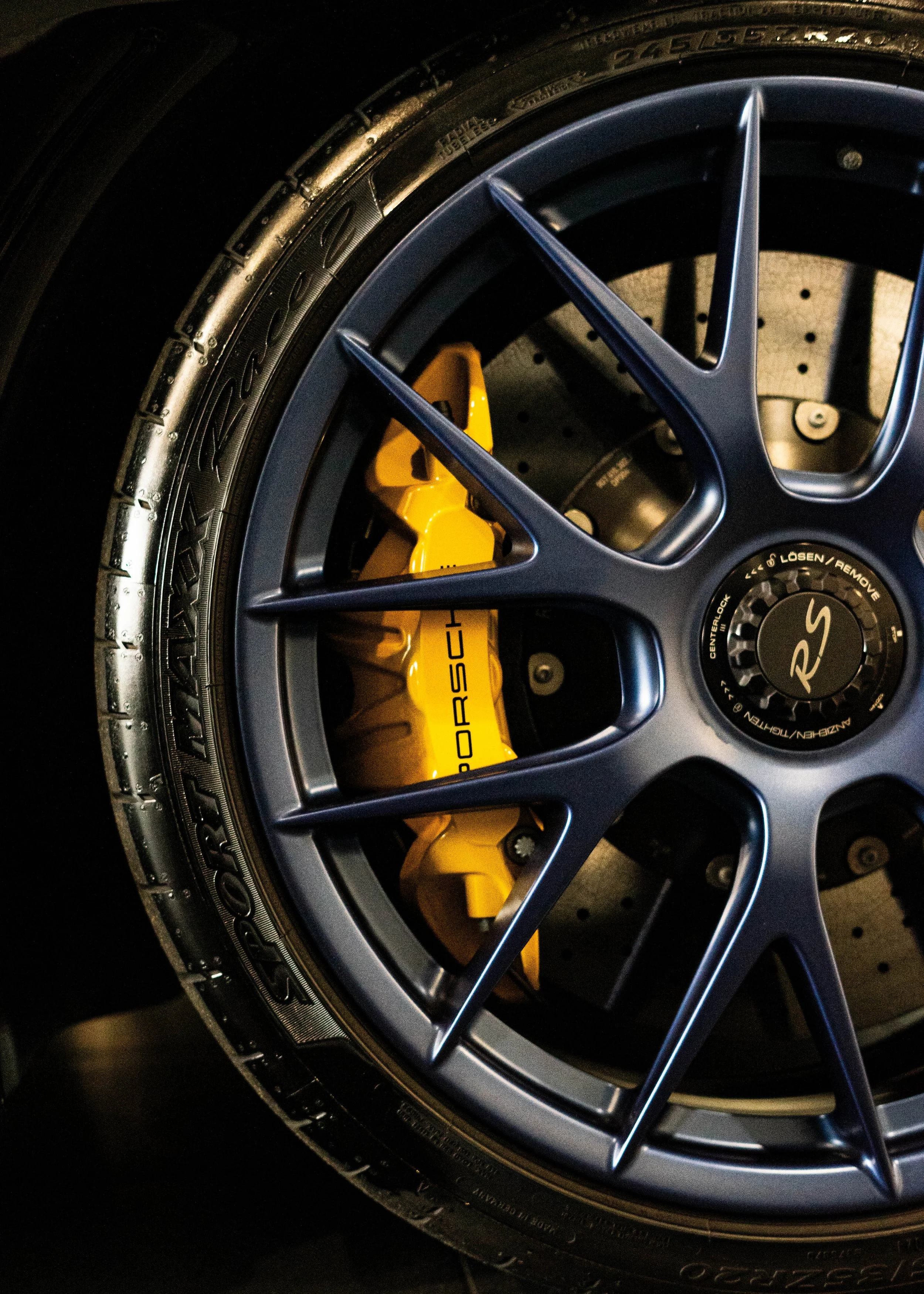 Close-up of a porsche wheel with a blue alloy rim and yellow brake caliper.